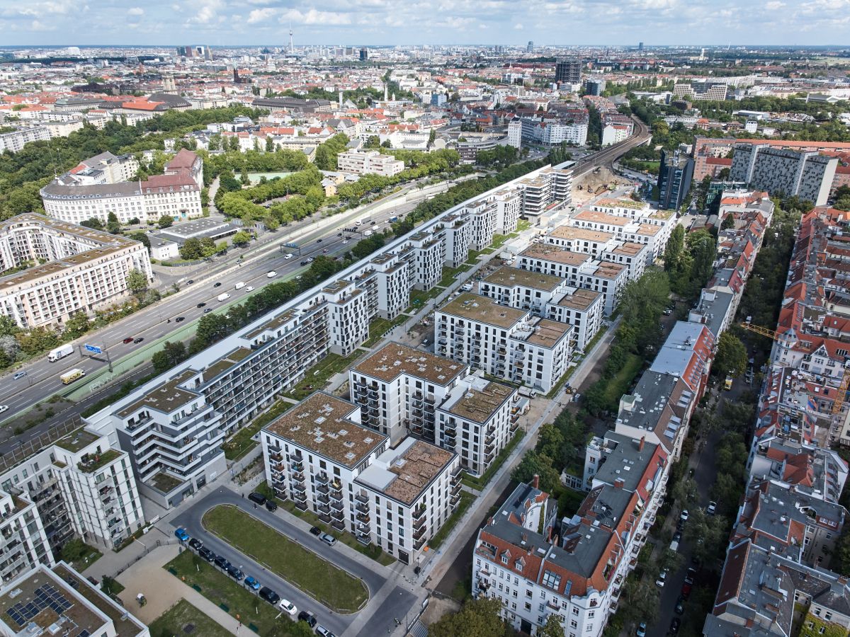Vogelperspektive  auf die acht Gebäuderiegel und einen Querriegel der Friedenauer Höhe mit Bahngleisen und Stadt im Hintergrund